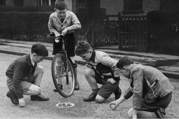 Bambini che giocano una partita a biglie per strada, 1947.